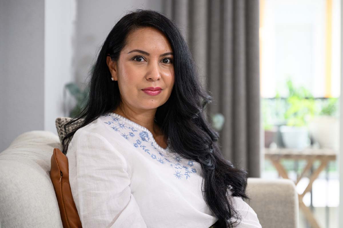 a woman sits on a sofa in front of some curtains after getting VTone in McAllen.