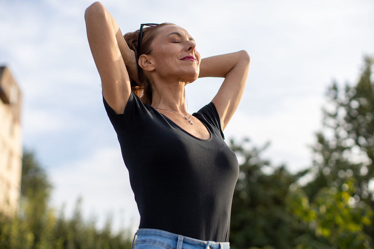 a woman lifts her head to the sun with her eyes closed and smiles after getting VTone in McAllen.